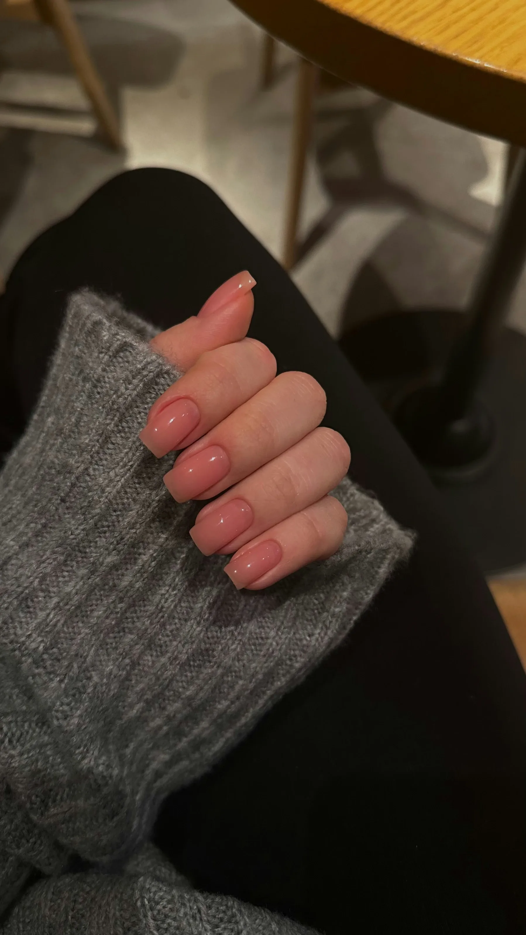 Glossy natural nude BIAB builder gel overlay resting on a soft knit sleeve