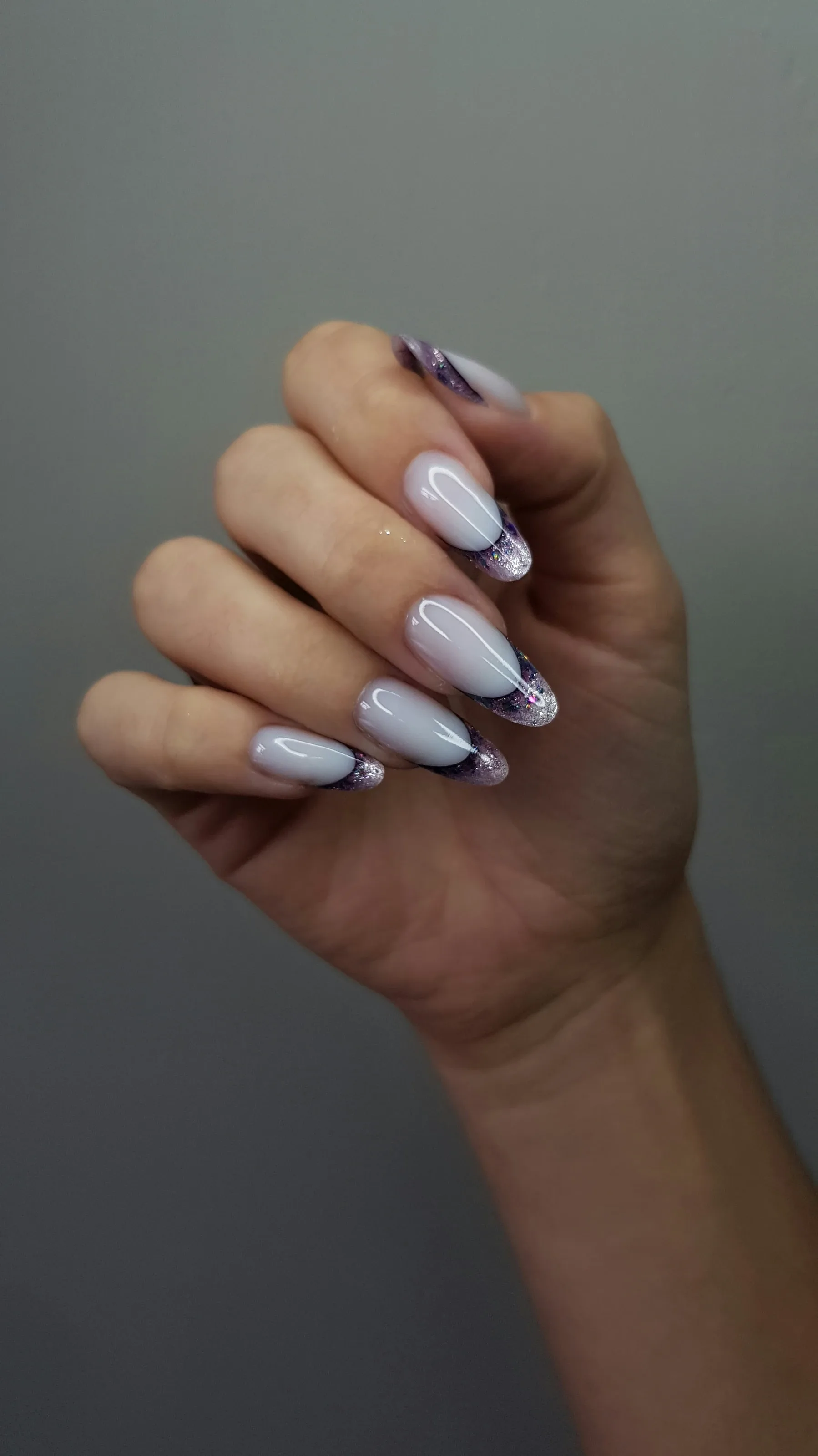 Almond shaped nails featuring a sheer lilac base with dark micro-French tips